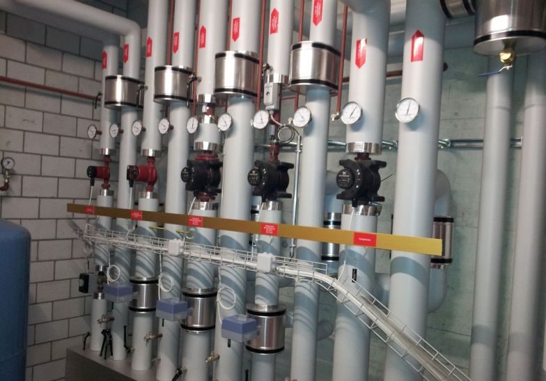 Pumpengruppen mit gedämmten Leitungen an einer Backsteinwand
