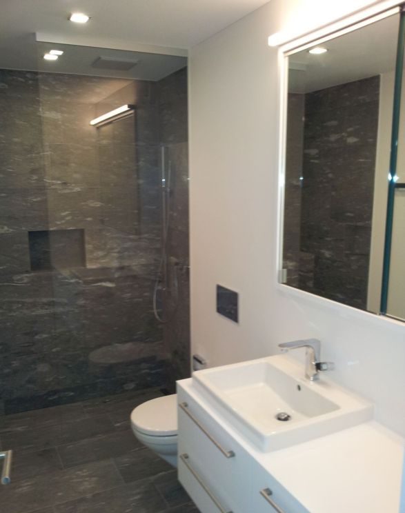 Bad mit Dusche hinter Glas, Waschtisch und Wand-WC in dunklem Stein