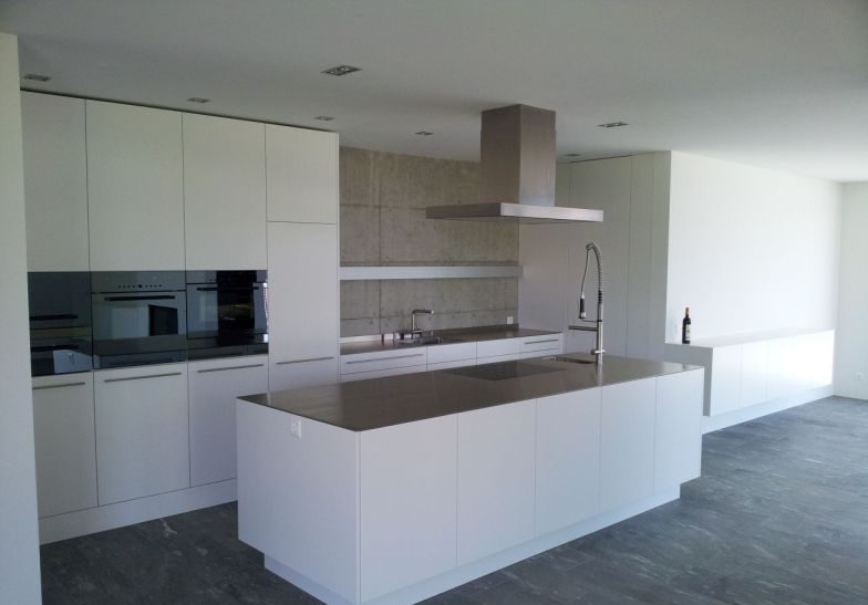 Weisse Küche mit Kochinsel auf dunklem Schieferboden
