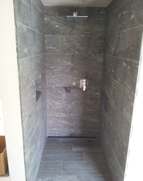 Dusche mit Wandfliesen aus dunklem Stein